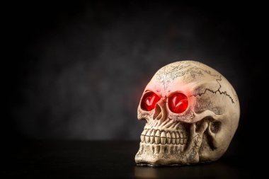 Karanlık arka planda siyah bir masanın üzerinde cadılar bayramı kafatası.