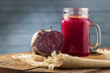 Ahşap masada cam bir fincanda kırmızı pancar suyu.