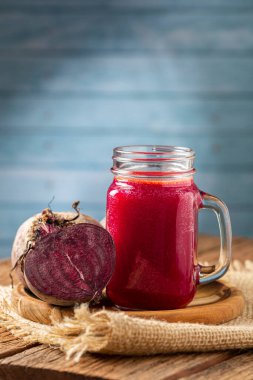 Ahşap masada cam bir fincanda kırmızı pancar suyu.