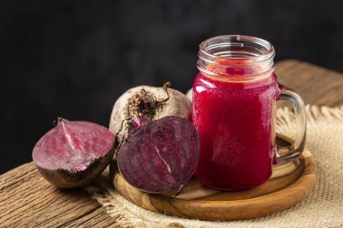 Ahşap masada cam bir fincanda kırmızı pancar suyu.