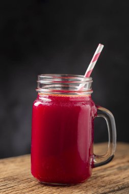 Ahşap masada cam bir fincanda kırmızı pancar suyu.