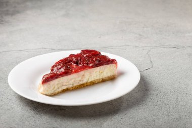 Masadaki beyaz yemek takımında çilekli cheesecake..