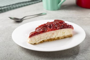 Masadaki beyaz yemek takımında çilekli cheesecake..