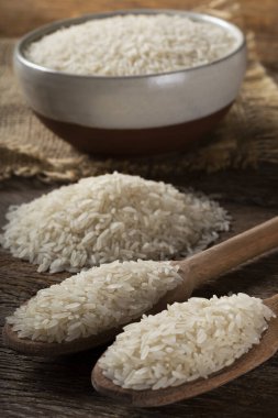 Kahverengi ahşap arka planda seramik bir kasede çiğ beyaz pirinç..