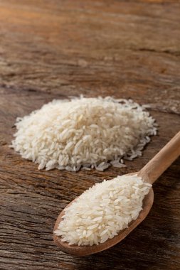 Kahverengi ahşap arka planda seramik bir kasede çiğ beyaz pirinç..