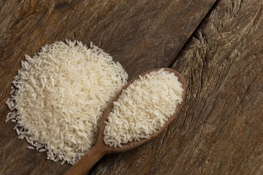 Kahverengi ahşap arka planda seramik bir kasede çiğ beyaz pirinç..