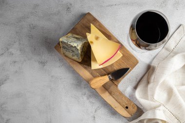 bir bardak kırmızı şarap ile peynir kurulu.