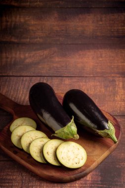 Masadaki kesme tahtasının üzerinde dilimlenmiş patlıcan..