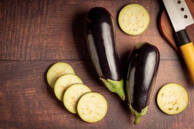 Masadaki kesme tahtasının üzerinde dilimlenmiş patlıcan..