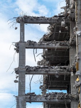 Kısmen yıkılmış bir bina bulutlu bir gökyüzüne karşı duruyor, açığa çıkan beton ve demiri ortaya çıkarıyor. Kalıntılar devam eden kentsel dönüşüm ve inşaat faaliyetlerini gösteriyor.