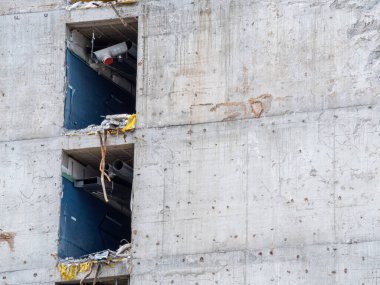 Bitmemiş beton bina, inşaat malzemelerini ortaya çıkaran açıkta kalan duvarları ve açıkları gösteriyor. Sitede, hareketli bir kentsel alanda devam eden gelişmeler yer alıyor.