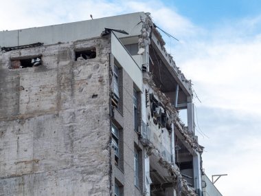 Kısmen çökmüş bir bina, bir depremin ardından ortaya çıkan döküntü ve döküntüleri ortaya çıkarıyor. Yapısal hasar, kentsel çevrenin kırılganlığını vurguluyor.