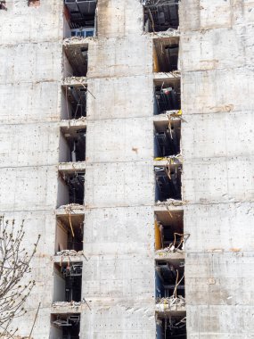 İşçiler, beton iskelet ve inşaat malzemelerini ortaya çıkararak çok katlı bir binayı restore ediyorlar. Yapı, devam eden gelişmeyi yansıtan kentsel bir çevrede duruyor..