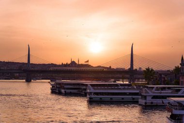 İstanbul şehir manzarası - gün batımında feribot ile Golden Horn denizinin panoramik manzarası. Günbatımında İstanbul 'un güneşli manzarası. Köprü ve sıcak ışıkla.