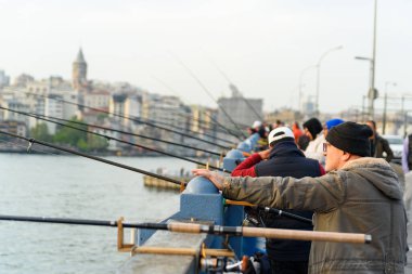 İstanbul, Türkiye - 10 Mayıs 2023: balıkçılar boğazdaki ikonik Galata Köprüsü üzerinde oltaları ile balık tutarken görülüyor. İstanbul 'da günlük yaşam sahnesi.