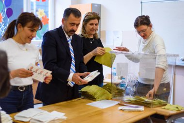 İstanbul, Türkiye - 14 Mayıs 2023: İl merkezindeki Buyuk Esma okulunda yapılan seçimlerde oy pusulası alırken oy kullanma görevlileri görülüyor.