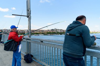 İstanbul, Türkiye - 10 Mayıs 2023: balıkçılar boğazdaki ikonik Galata Köprüsü üzerinde oltaları ile balık tutarken görülüyor. İstanbul 'da günlük yaşam sahnesi.