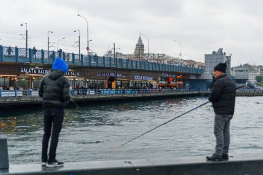İstanbul, Türkiye - 10 Mayıs 2023: balıkçılar boğazdaki ikonik Galata Köprüsü üzerinde oltaları ile balık tutarken görülüyor. İstanbul 'da günlük yaşam sahnesi.