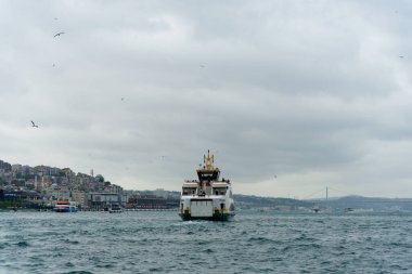 İstanbul, Türkiye - 14 Mat 2023: Çevrimiçi feribot gün batımında Golden Horn kanalını ve şehir manzarasını geçerken görülüyor. İstanbul 'da toplu taşıma. Türkiye 'ye git. Boğaz üzerinde altın saat ve feribot.