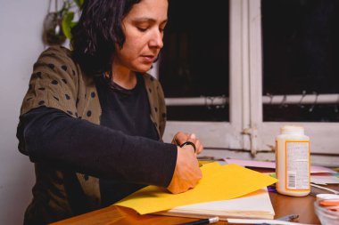 Yetişkin bir kadın kağıttan ev yapımı albüm yapıyor. DIY kağıt el işi, hobi konsepti, hediye fikri, el işi nitelikleri, ev yapımı, yaratıcılık süreci, yaratıcılık.