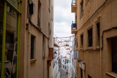 Sitges kasabasında 20 Ağustos 2022 'de İspanya' nın Sitges şehrinde beyaz duvarlı eski dar bir cadde görüldü..