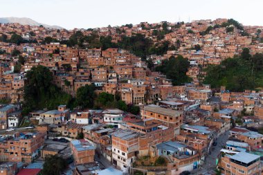 Günbatımında Venezuela ve Latin Amerika 'nın en büyük gecekondu mahallesi olan Petare Mahallesi ile Avila Dağı' nın arka planında hava manzarası.