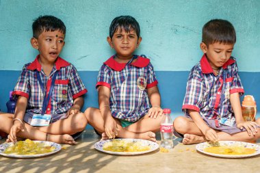 Kolkata, Hindistan - 20 Ekim 2024: Kızılderili okulunda öğle yemeği yiyen üniformalı çocuklar. Büyüme, eğitim, beslenme ve çocukluk kavramı