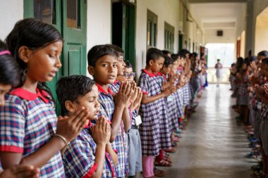 Kolkata, Hindistan - 20 Ekim 2024: üniformalı çocuklar Hint okulu sabahı rutini için dua edip milli marşı söylüyorlar. Büyüme, eğitim, ilham ve çocukluk kavramı