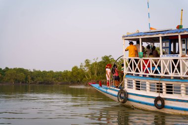 Sundarbans, Hindistan - 20 Ekim 2023: geleneksel bir turist teknesinin gün batımında bir su kanalında yelken açtığı görülüyor. Batı Bengal 'de Sundarbans' da safari turizmi kavramı. Kaplan rezervi.