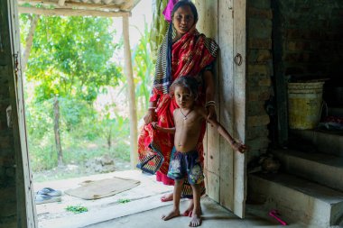 Sundarbans, Hindistan - 23 Ekim 2023: Hindistan 'ın kırsal kesimindeki küçük bir köyde evinin içinde geleneksel bir sari giyen ve kameraya bakan genç bir Hintli kadının portresi