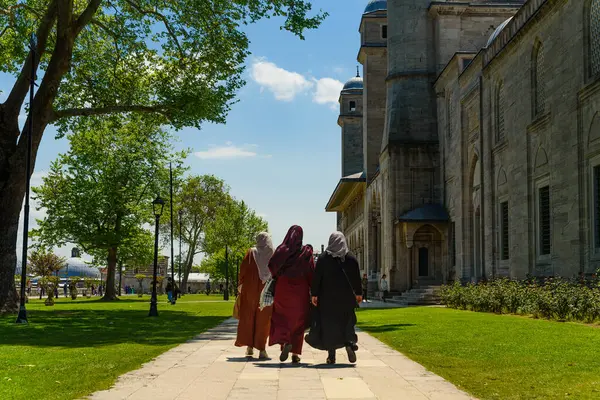 Güneşli bir günde, İstanbul 'daki bir caminin önünde peçeli Müslüman kadınlar birlikte yürüyor. İstanbul 'da günlük yaşam
