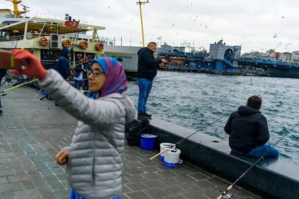 İstanbul, Türkiye - 10 Mayıs 2023: balıkçılar boğazdaki ikonik Galata Köprüsü üzerinde oltaları ile balık tutarken görülüyor. İstanbul 'da günlük yaşam sahnesi.