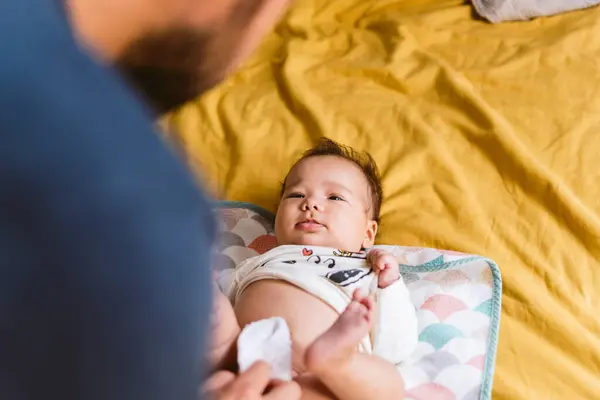 Genç baba evde bebek bezi değiştiriyor. Modern bir ailede günlük yaşam