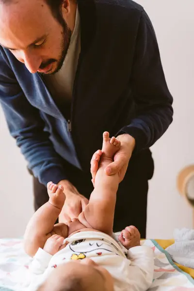Genç baba evde bebek bezi değiştiriyor. Modern bir ailede günlük yaşam
