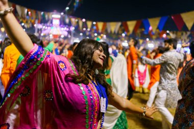 Baroda, India - 17th October 2023: Indian people in traditional sari and kurta dresses dance the Garba music during the hindu Navratri festival to honor the goddess Durga. clipart