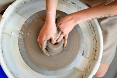 Seramistin ellerini kapatıyoruz ve seramik şekillendiriyoruz. Torna tezgahında ya da çömlekçi çarkında doğal ışık alan bir çömlek atölyesinde.