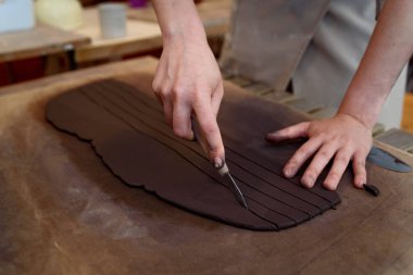 Kadın elleriyle çömlek atölyesinde seramik kesiyor çiğ seramik vazo ve kilden ot yapıyor. Doğal ışık kazıma, düzleştirme, şekillendirme ve yontma ile çömlek atölyesi. Kil tenceresi yapmak