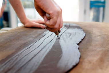 Kahverengi kil çanak çömlek atölyesini keserek çiğ seramik vazo ve kilden ot yapmak. Doğal ışık kazıma, düzleştirme, şekillendirme ve yontma ile çömlek atölyesi. Kil tenceresi yapmak