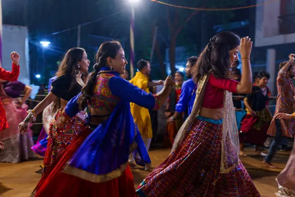 Baroda, Hindistan - 17 Ekim 2023: Geleneksel sari ve kurta elbiseli Hintli insanlar Hindu Navratri festivali sırasında Tanrıça Durga 'yı onurlandırmak için Garba müziği yapıyorlar..