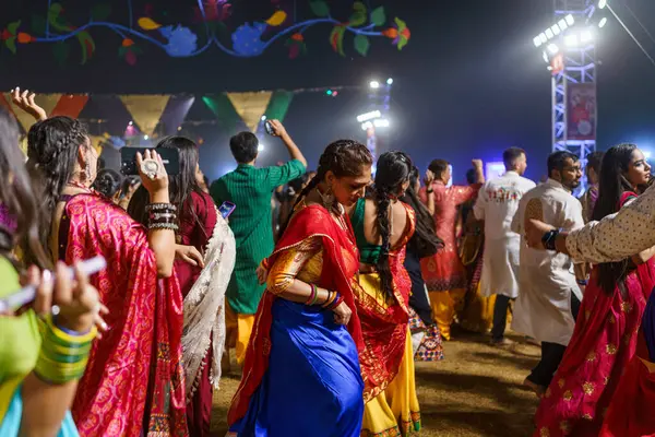 Baroda, Hindistan - 17 Ekim 2023: Geleneksel sari ve kurta elbiseli Hintli insanlar Hindu Navratri festivali sırasında Tanrıça Durga 'yı onurlandırmak için Garba müziği yapıyorlar..