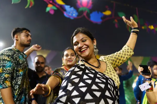 Baroda, Hindistan - 17 Ekim 2023: Geleneksel sari ve kurta elbiseli Hintli insanlar Hindu Navratri festivali sırasında Tanrıça Durga 'yı onurlandırmak için Garba müziği yapıyorlar..