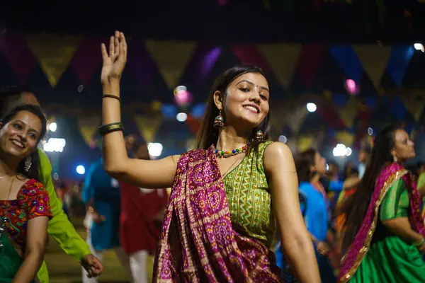 Baroda, Hindistan - 17 Ekim 2023: Geleneksel sari ve kurta elbiseli Hintli insanlar Hindu Navratri festivali sırasında Tanrıça Durga 'yı onurlandırmak için Garba müziği yapıyorlar..