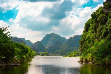 Ninh Binh Vadisi 'nin gün batımı manzarası ve Tam Coc nehri dağlarda. Barışçıl Vietnam dağları gün batımında sıcacık bir ışık ve kayıkla görünür..