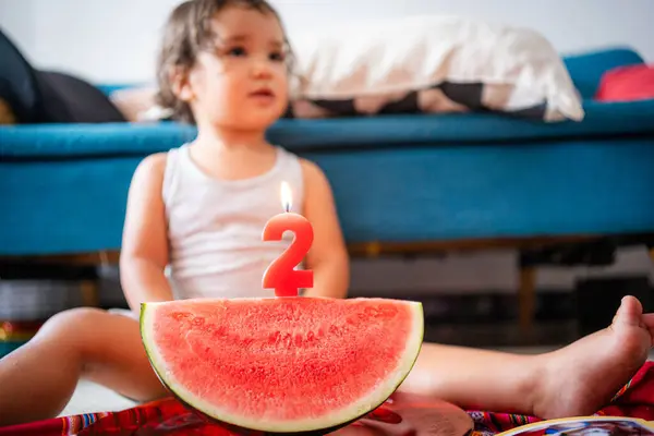 2 yaşındaki bebek doğum gününü basit bir karpuz dilimli pasta ve mumla kutluyor. Pastanın orijinal ve farklı alternatifleri. Çocukluk kavramı