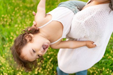 Yavru bebek, ilkbaharda bir çiçek tarlasında annesiyle oynarken, aşağıdan görülmüş. Anne ve kızın birbirine bağlanması ve dışarıda birlikte oyun oynaması, gülümsemesi ve mutlulukla hareket etmesi kavramı.