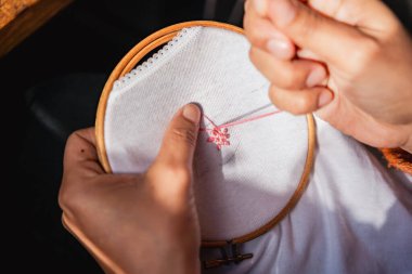 close up of woman hands embroidering using embroidery hoop and sewing kit on canvass. concept of at home craft activity clipart