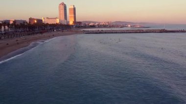Gün batımında Barceloneta sahilinin insansız hava aracı görüntüsü. Akdeniz manzaralı karanlık bir şehir manzarası. Günbatımı silüeti. Marina Caddesi ve Olimpik Limanı