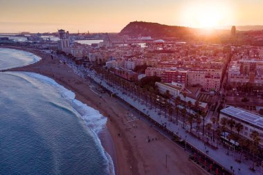 Gün batımında Barcelona sahilinin hava aracı görüntüsü. Barceloneta plajı yakınlarındaki karanlık şehir manzarası. Günbatımı silüeti. Marina Caddesi ve Olimpik Limanı