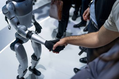 Unitree şirketinin bir insansı robotu insanlarla tokalaşırken görülüyor. İnsan ve robot etkileşimi ve robot mühendisliği kavramı