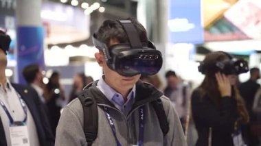 Barselona, İspanya - 28 Şubat 2025: Sanal gerçeklik kulaklığı kullanan insanlar bir ticaret fuarında görülüyor. VR dijital simülasyon kavramı, gelişmiş teknoloji sergileniyor